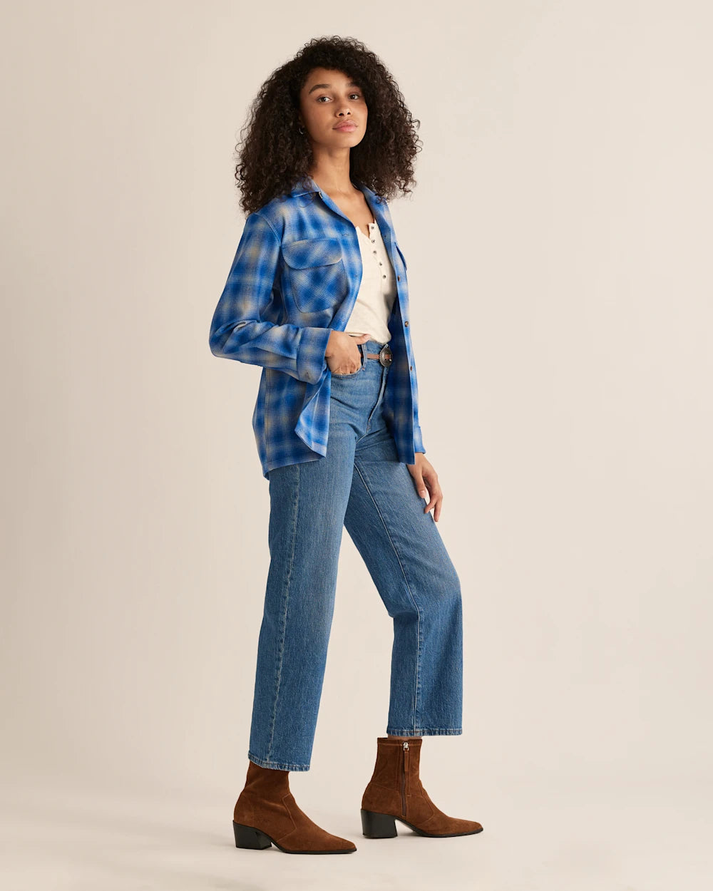 Side View of A woman wearing a Pendleton Women's Navy Mix Ombre plaid shirt with a mandarin collar, paired with blue jeans. She is posing against a plain background.