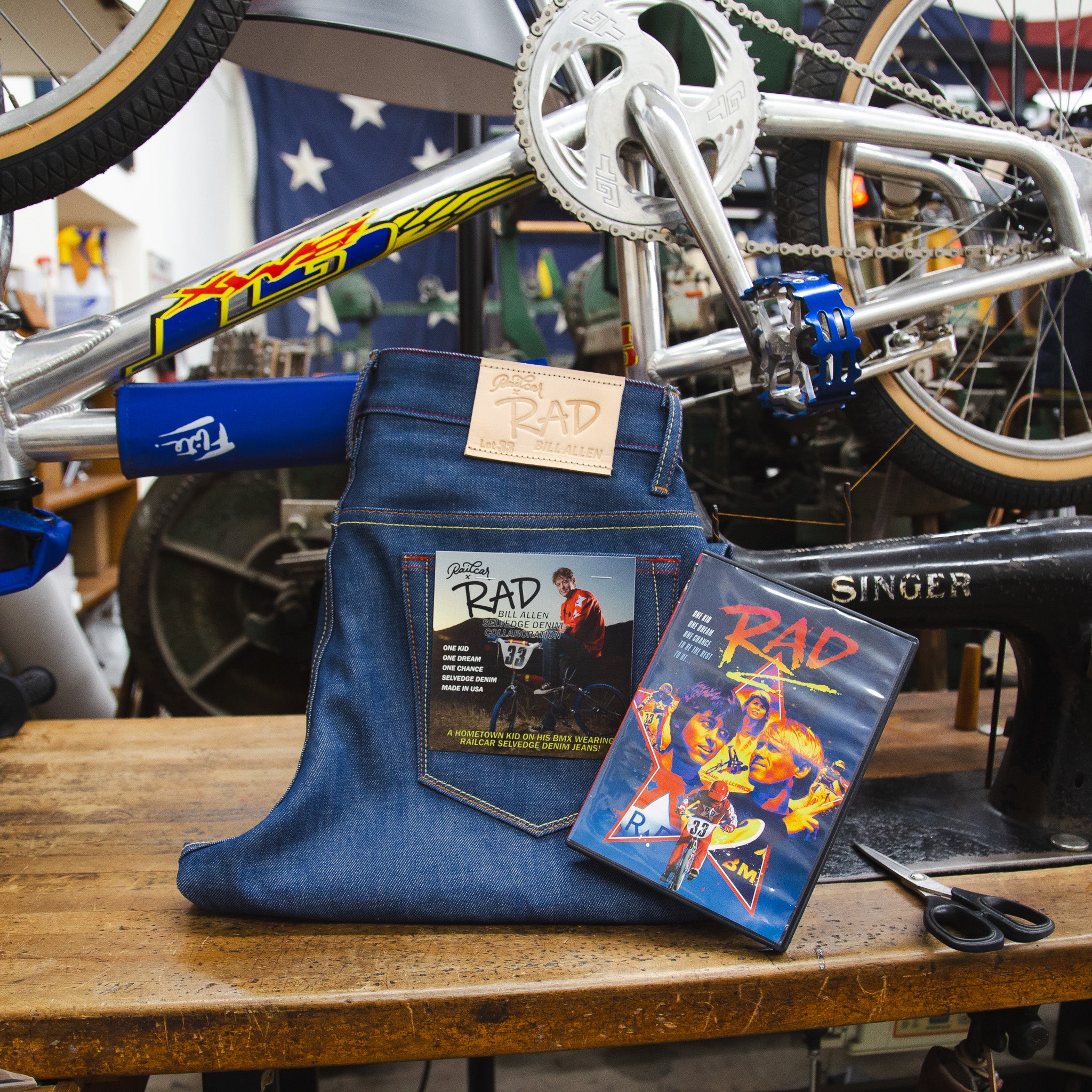Folded pair of Railcar X Rad Bill Allen Collaboration #1 Jeans next to copy of RAD on DVD