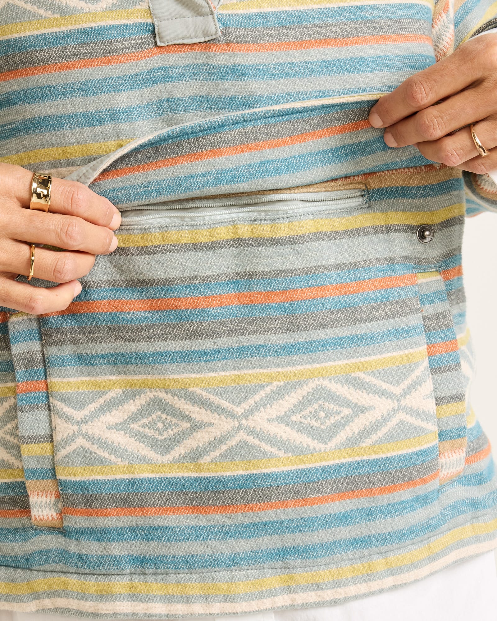 Close-up of a colorful striped fabric with geometric patterns, held by hands.