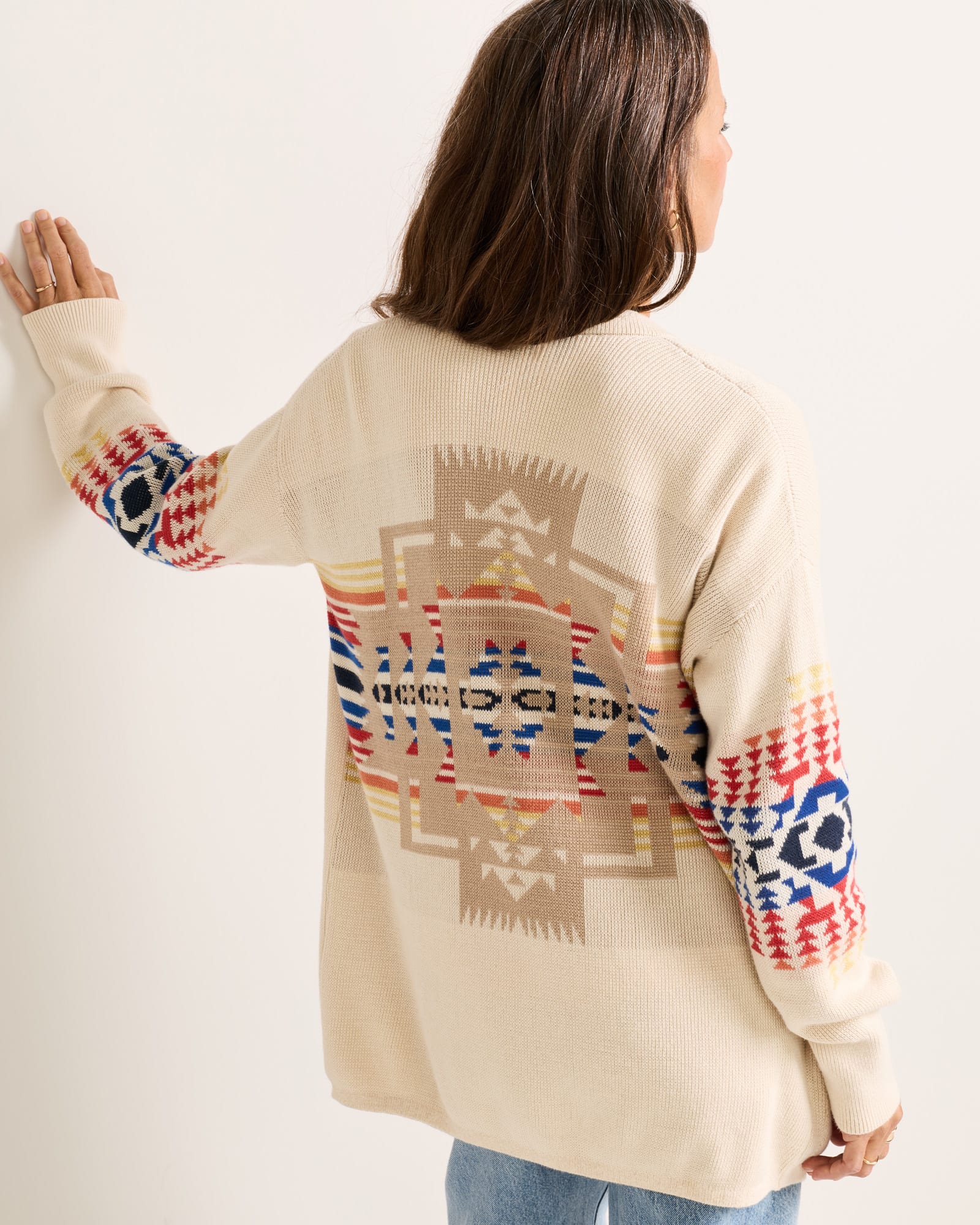 Person wearing a cream-colored sweater with geometric patterns on a white background