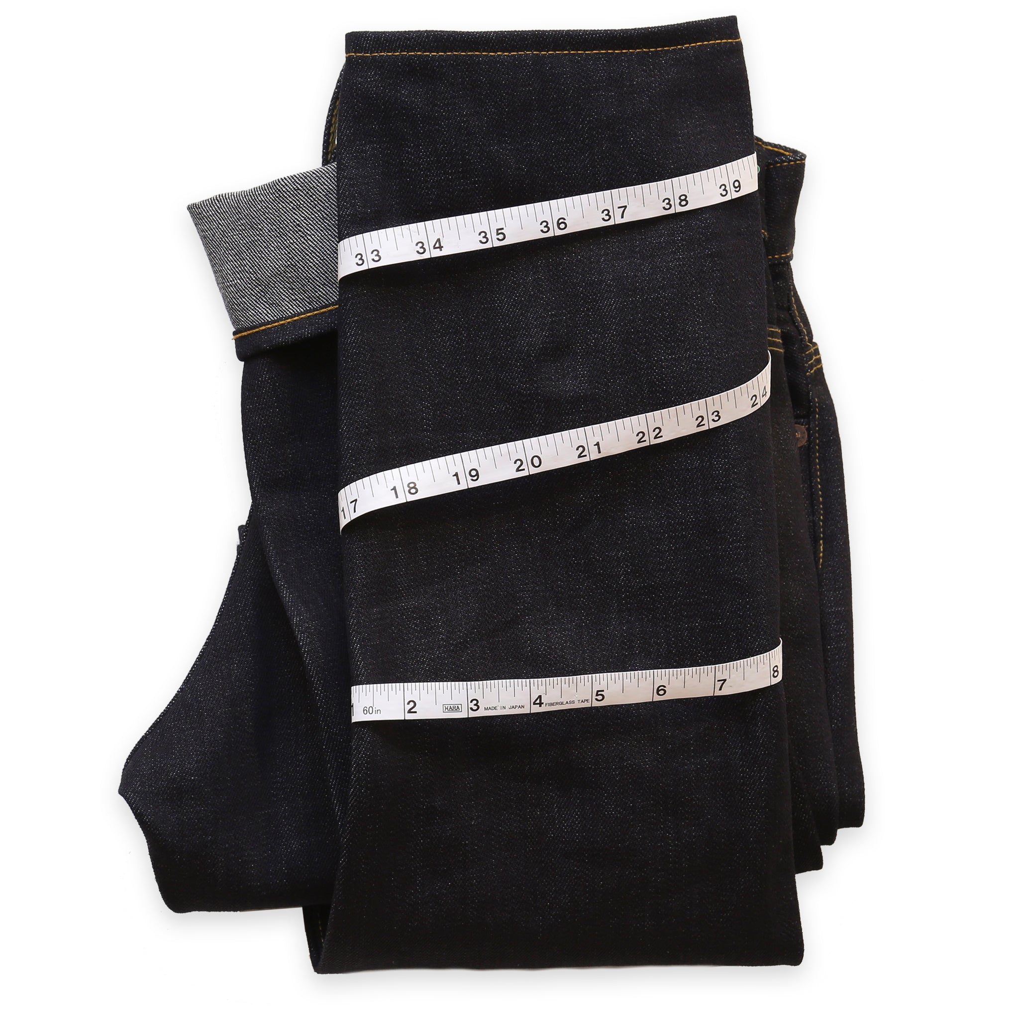 A pair of jeans folded with a measuring tape wrapped around the leg