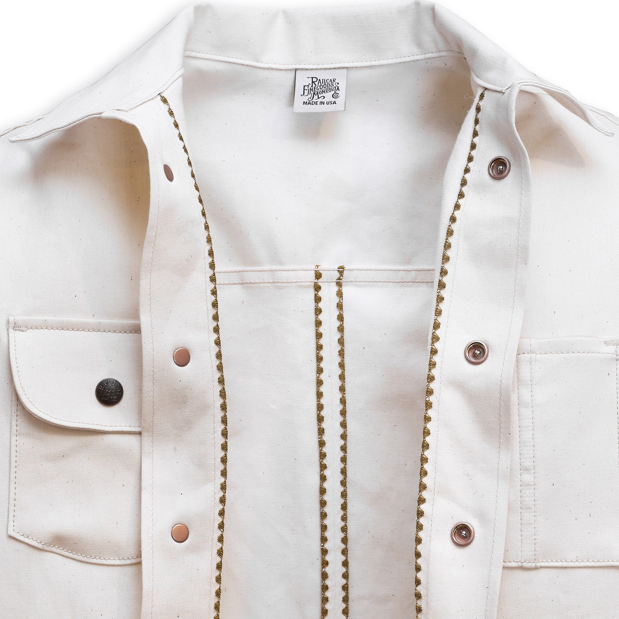 Interior of a natural seed chore coat with snap buttons, featuring a collar, front pockets, and shelling detail.