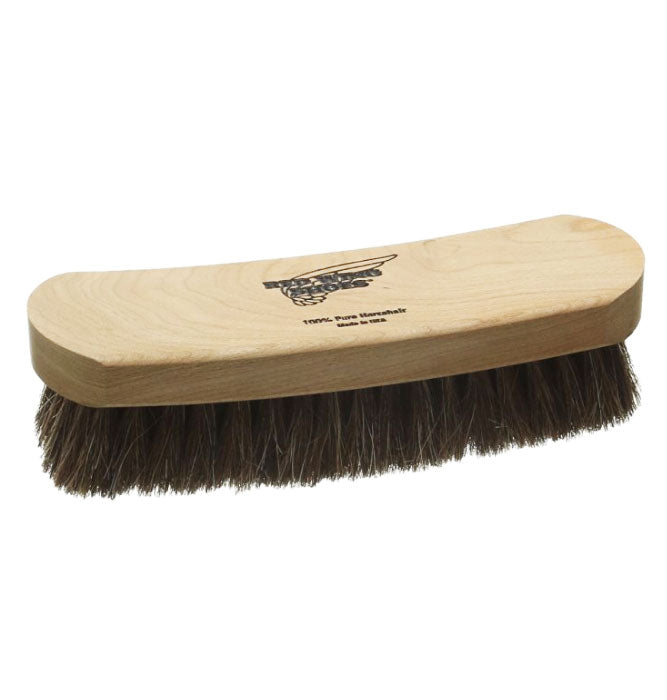 A wooden boot brush with bristles, featuring the Red Wing Heritage logo on the top.