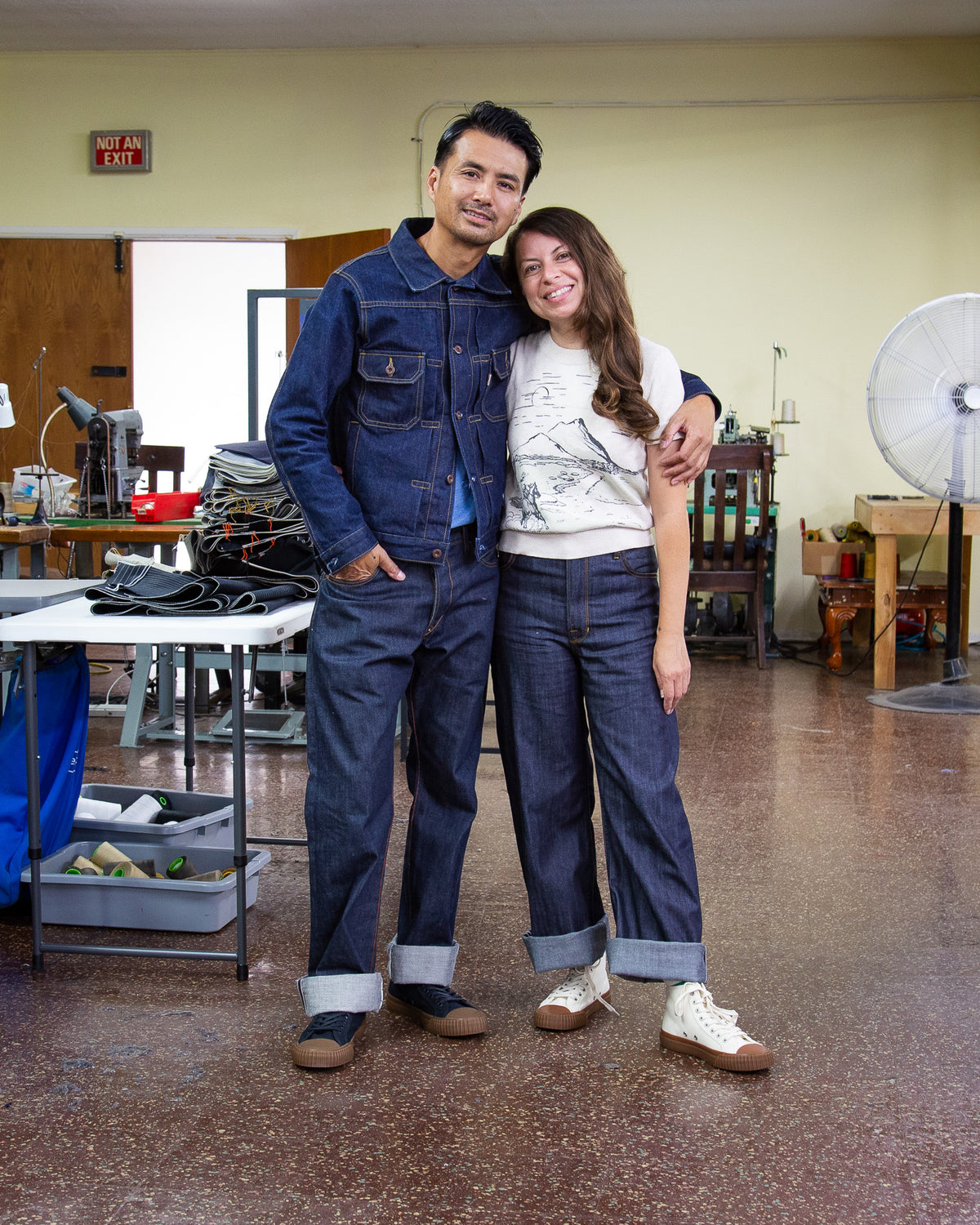 Railcar founder Steven Dang and Tawny Ortiz standing together in the El Monte workshop, both wearing Railcar denim