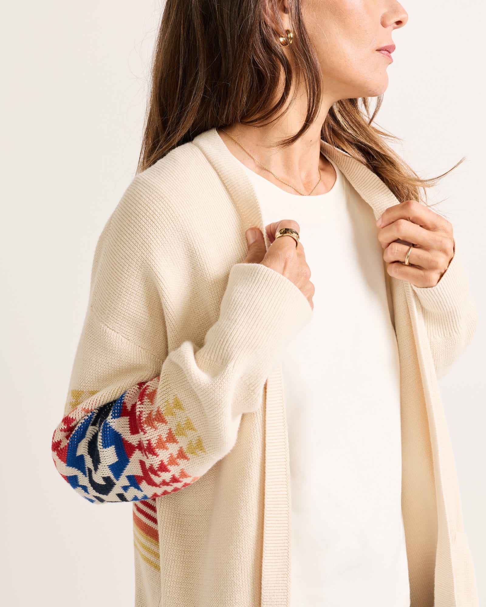Beige cardigan with colorful sleeves worn by a person on a light background